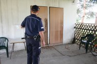 policjant ogląda zniszczone drzwi