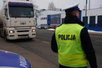 Na zdjęciu policjant w trakcie kontroli ciężarówki na drodze.